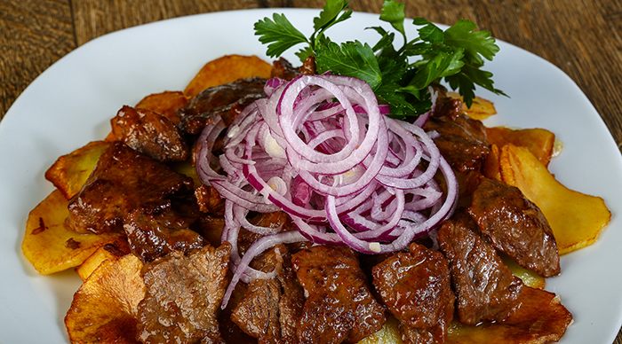 A plate of roast meat potatoes and green leaf