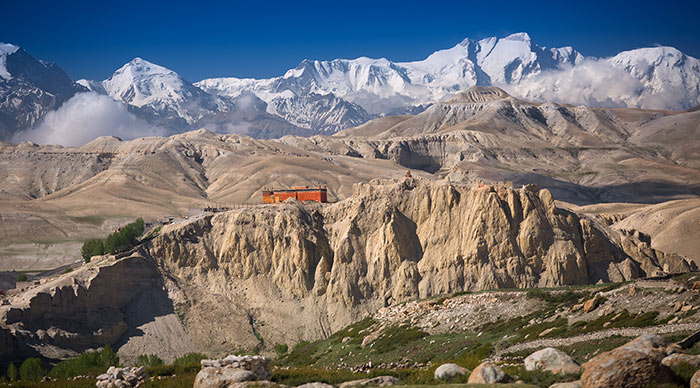 Buddhist monastery on the rocky hills with snowy mountains in Upper Mustang Nepal