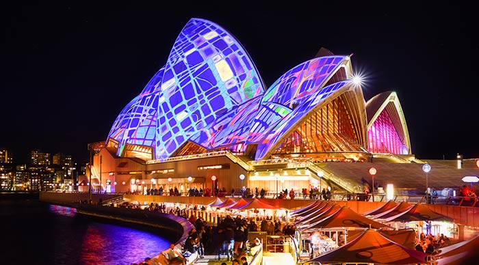 A view of Sydney Opera House illuminated with colourful light