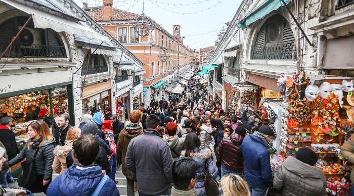 A view of the Rialto markets and Rialto Bridge full of tourists shopping and sightseeing in Venice Italy. The Rialto is the commercial and financial center of Venice.